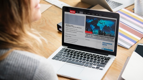 A woman looking at news items on a laptop.