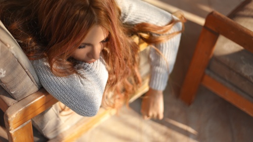 A woman sitting in a chair with her head resting on her arm.