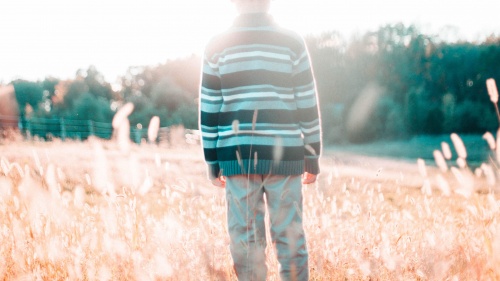 A young boy standing in a field.