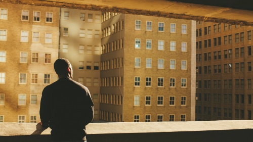 A person looking out over a wall at buildings in a city.