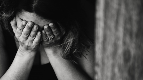 A woman holding her head in her hands grieving.