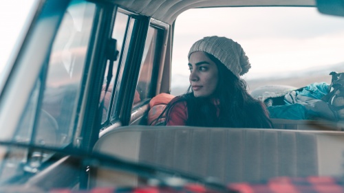 A woman sitting the backseat of a car.