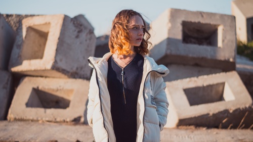 A young woman standing in front of a pile concrete blocks.