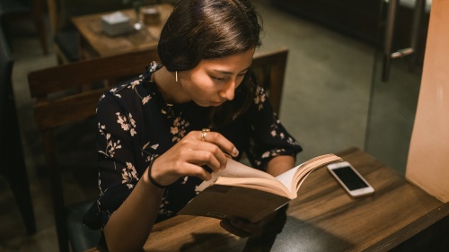 A woman reading a book in a cafe.