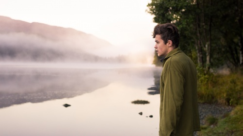 A young man looking out over a lake.