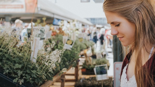 A woman working a Farmer's Market selling flowers.