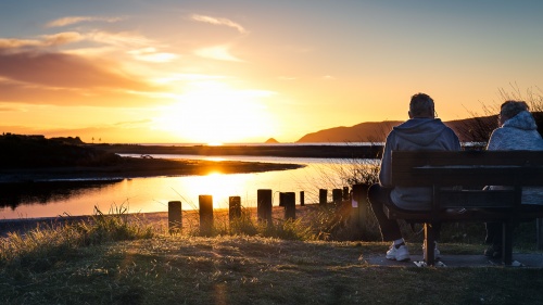 Two people sitting on a bench.