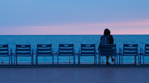 A person sitting watching the water of a sea.