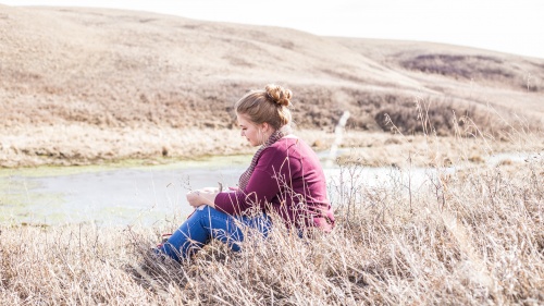 A woman sitting in a field of tall grass.