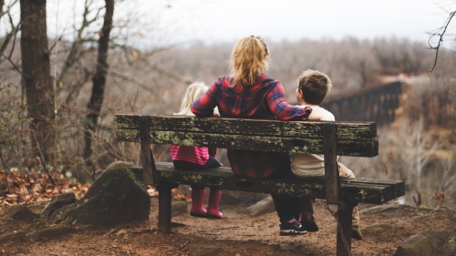 Photo of mother with two children on a bench.