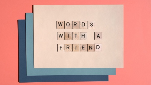 Layered cardstock paper in multiple colors with Scrabble tiles spelling the article title, words with a friend