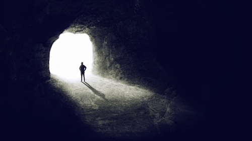 A man in a dark cave looking out from the entrance