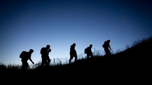 hiking people silhouetted against blue sky