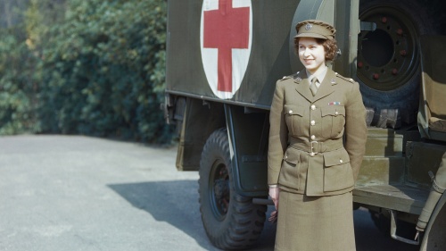 A photo of a young Queen Elizabeth standing in front of an army ambulance,