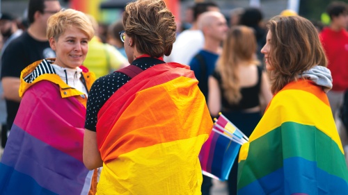 People with pride flags covering their shoulders.