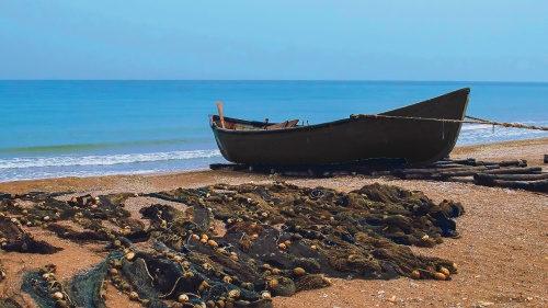 A boat on a sandy shore with nets.