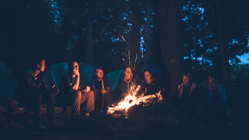 A group of young people around a campfire at night.