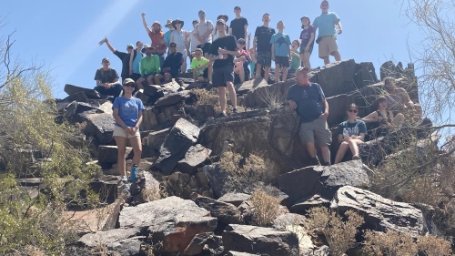 A group of hikers standing and seated on boulders