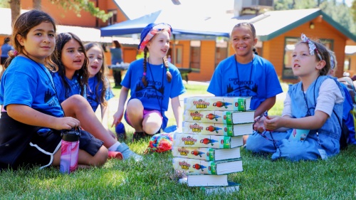 a group of girls sitting around a stack of Bibles