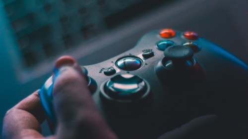 A pair of hands holding a gaming controller above a laptop keyboard