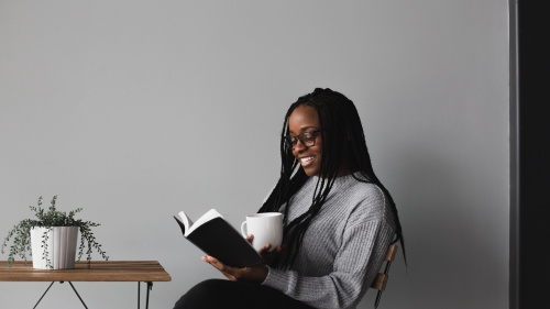 a woman holding a coffee cup and reading a Bible