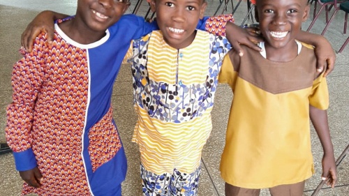 three children in traditional clothing standing arm in arm