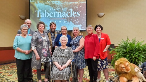 a group of brethren gathered in front of the Feast of Tabernacles banner