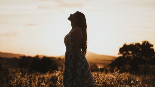 A woman standing in a field looking up.