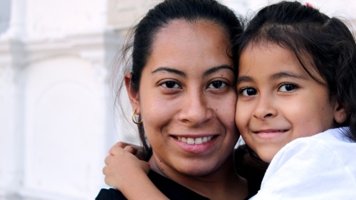 a mother holding her daughter in her arms; both are smiling