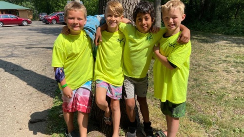 four boys standing outside wearing matching UYC shirts