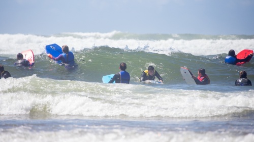 a group of teenagers with boogie boards among the waves