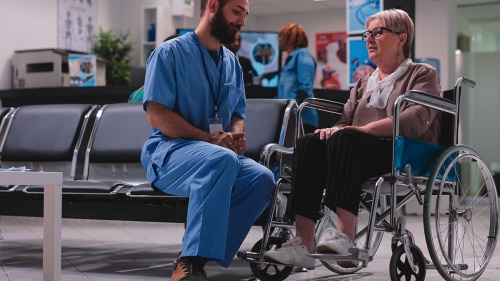 A doctor talking with a patient in a wheelchair. 