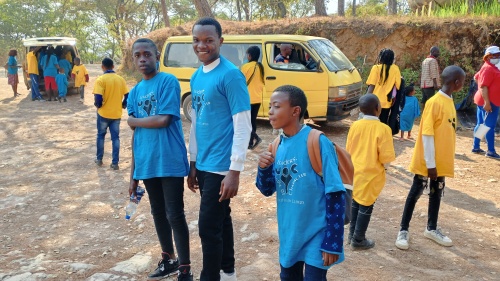 a group of children and teenagers standing outside in front of a bus