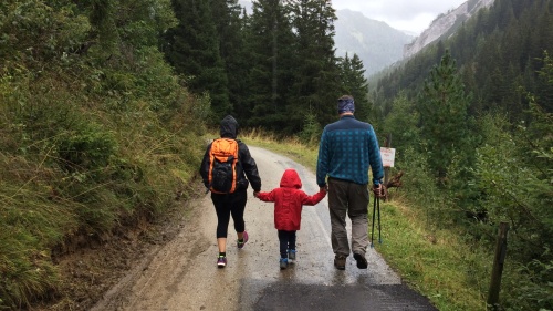 a family of three walking on a road in the mountains