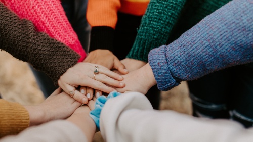 several hands extended to meet one another in a circle