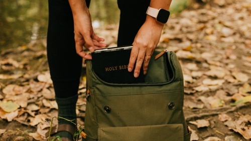 A person pulling their Bible out of the backpack. 