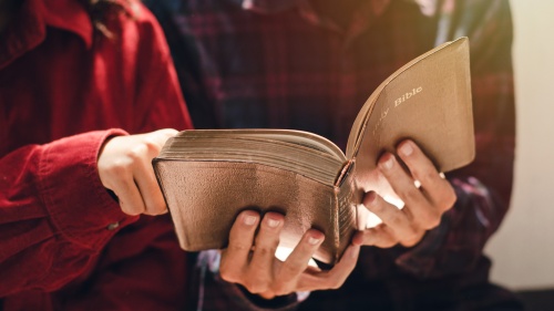 Two people looking at an open Bible.