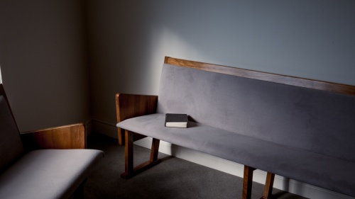 A church pew with a Bible on it.