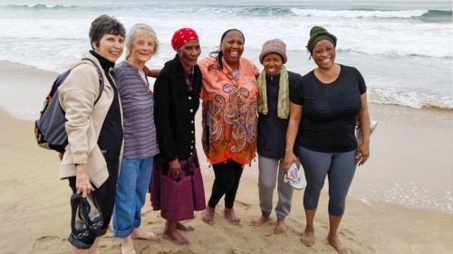 six women standing on the beach