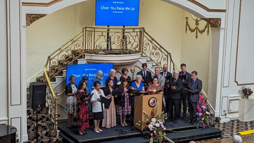 a choir standing at the front of a room to sing to an audience