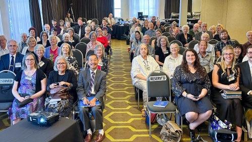 a room full of people seated for a Church service, viewed from the front of the room