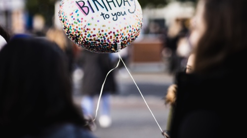 A person hold a balloon that says "Happy Birthday to you"