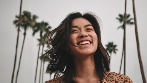 a smiling woman with palm trees in the background