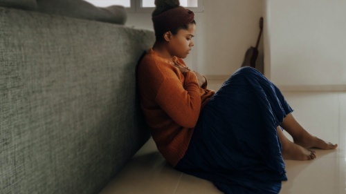 A woman sitting on the floor in thought.