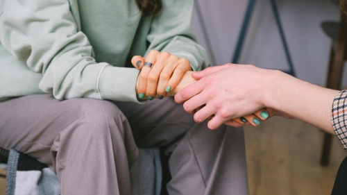 a woman extending a hand to another woman, sitting across from her