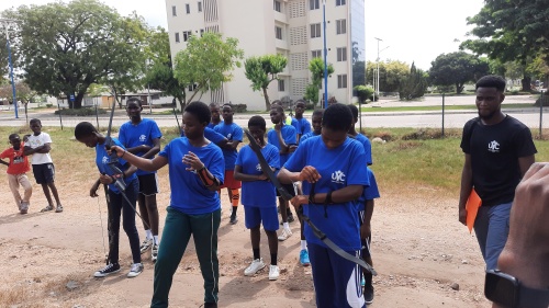 a group of teenagers with archery equipment outdoors