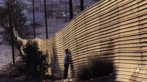 People standing by a border wall.