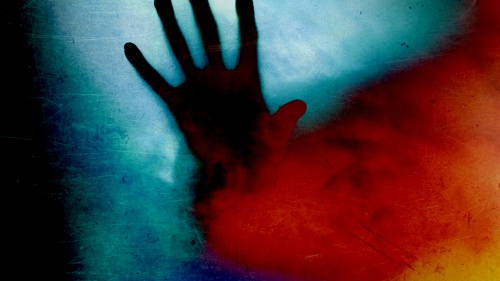 A photos illustration of a hand through red smoke.