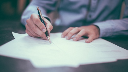 A man writing with a pencil on paper.