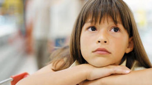 A young girl leaning on a shopping cart.